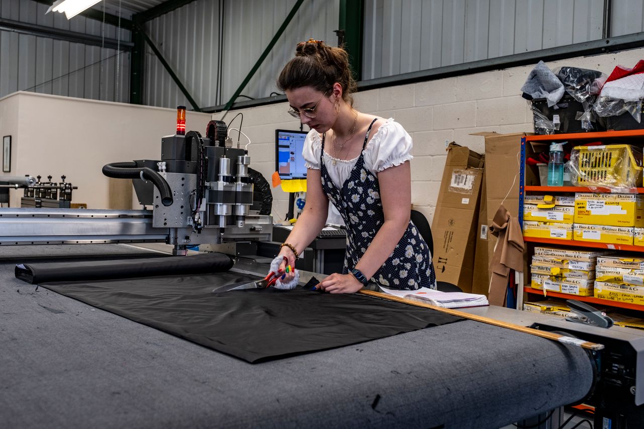 services-03 Female tailor cutting fabric in a factory environment, demonstrating precision and craftsmanship.