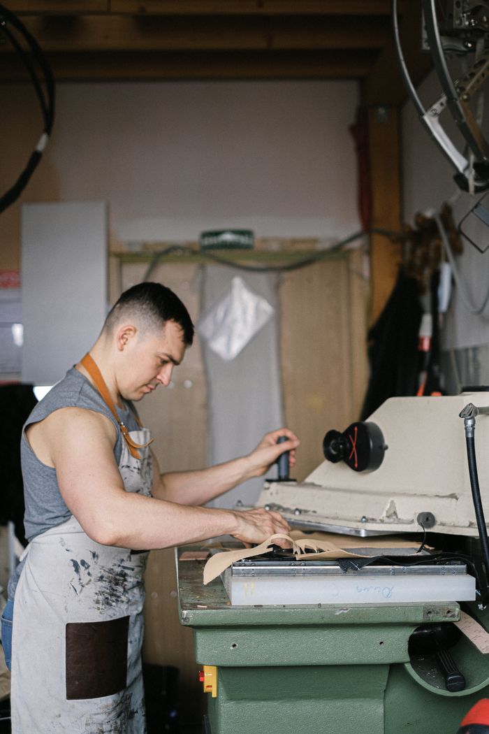 why-choose-us-03 A dedicated artisan wearing an apron operates machinery in a workshop setting.