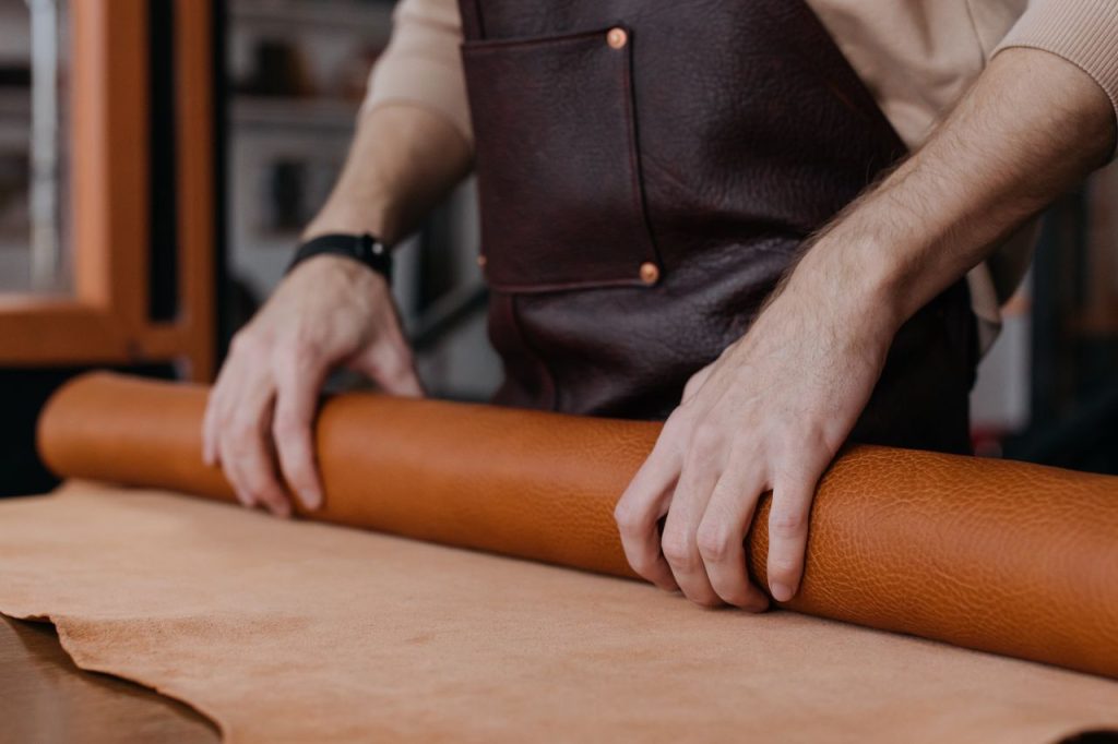 Close-up of hands working with leather, showcasing craftsmanship in an artisan workshop.